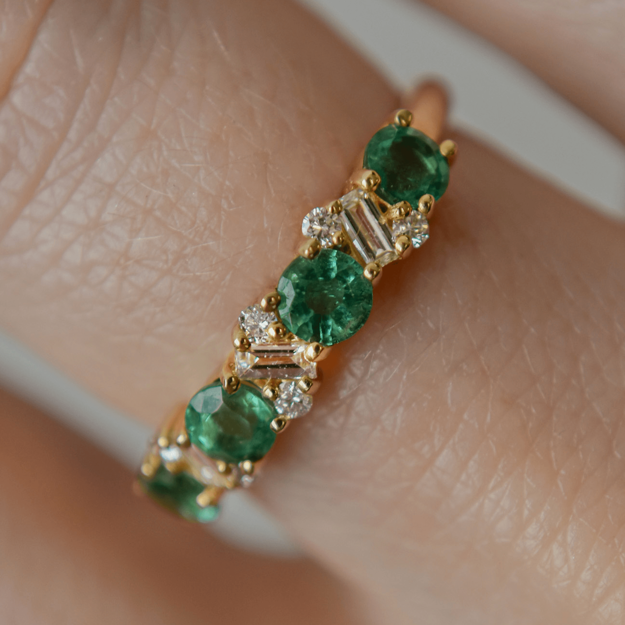 EMERALD WHISPER złoty pierścionek z okrągłymi szmaragdami, diamentami w szlifie bagietka i brylantami